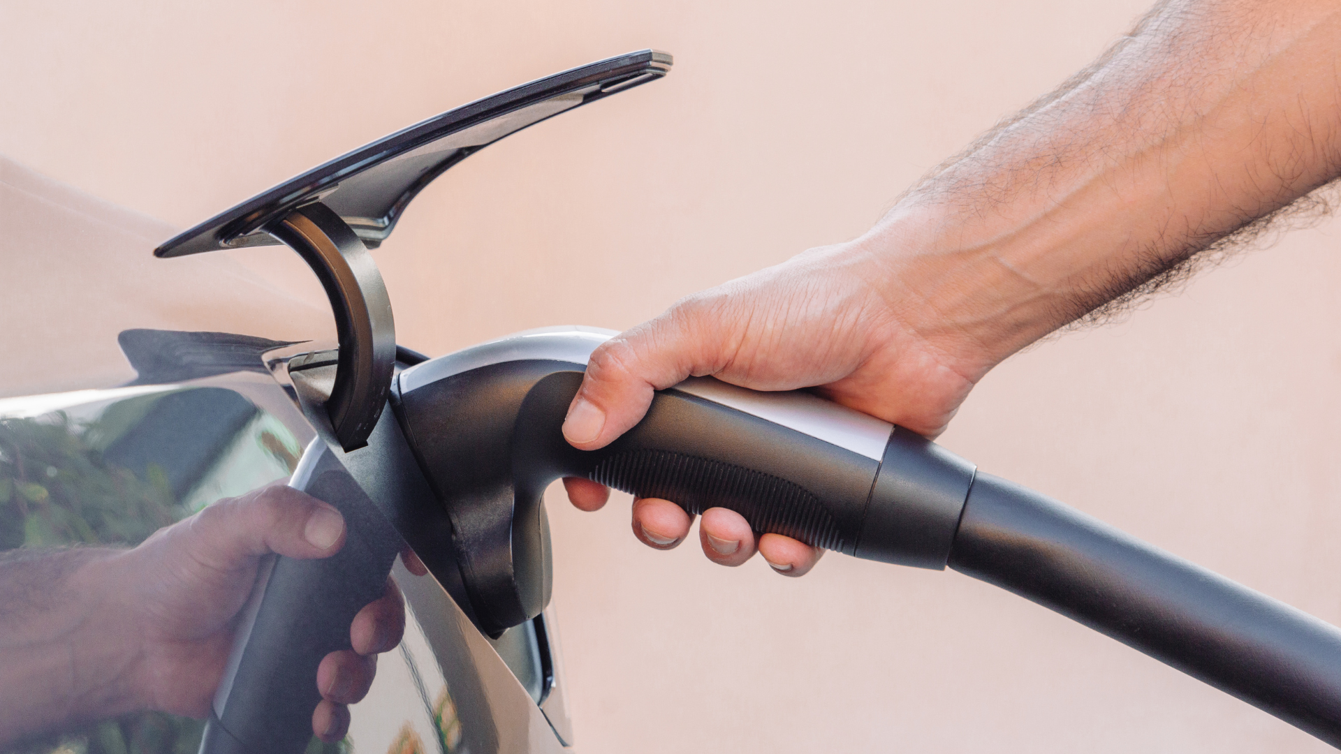 Un Tesla Model 3 cargando en un garaje doméstico con un cargador inteligente de pared de Lumox Energy, controlado por una mujer con su smartphone.